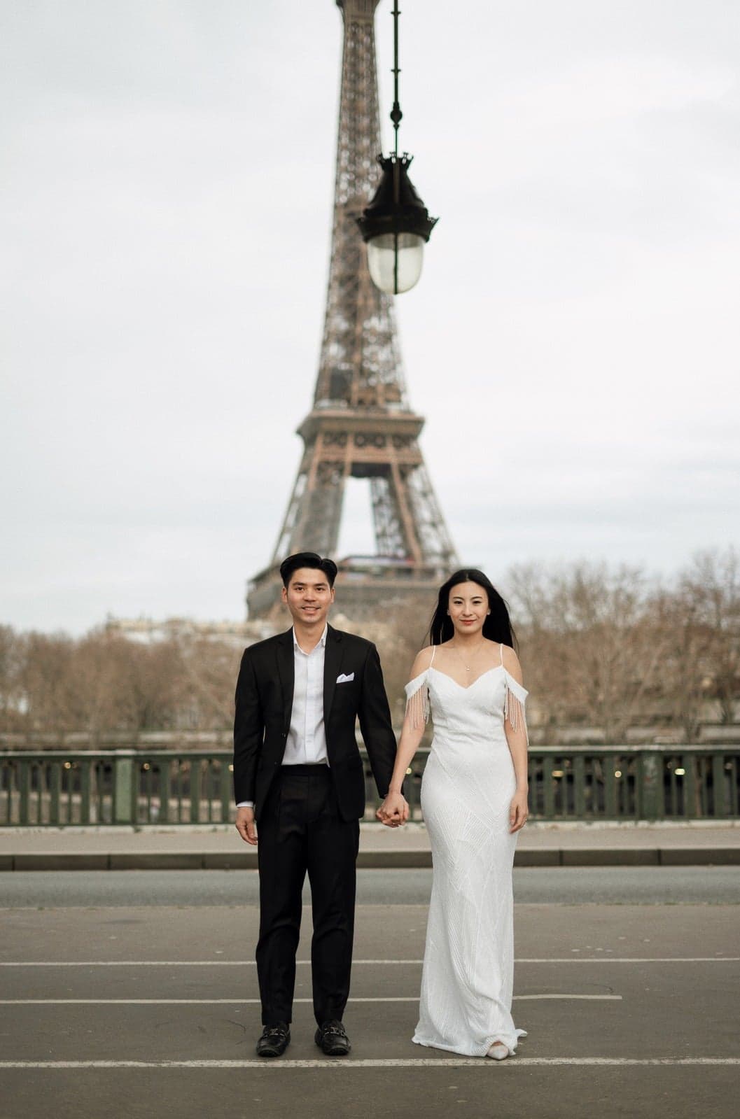 Suthida and Thanapat holding hands in front of the Eiffel Tower